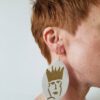 A person with red hair wearing earrings.