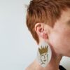 A woman with red hair wearing large earrings.